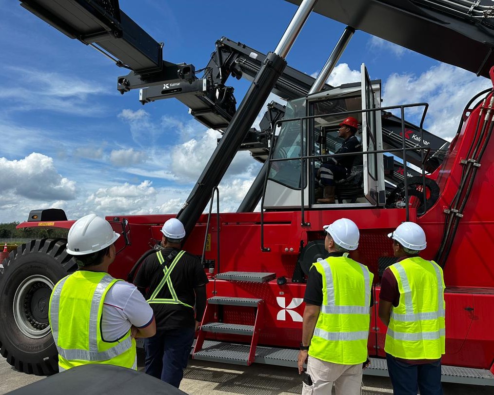 Mach 1 after-sales team providing operator training for a DRU450 reach stacker, DCU80 empty container handler, and TL2 terminal tractor at Perlis Inland Port.